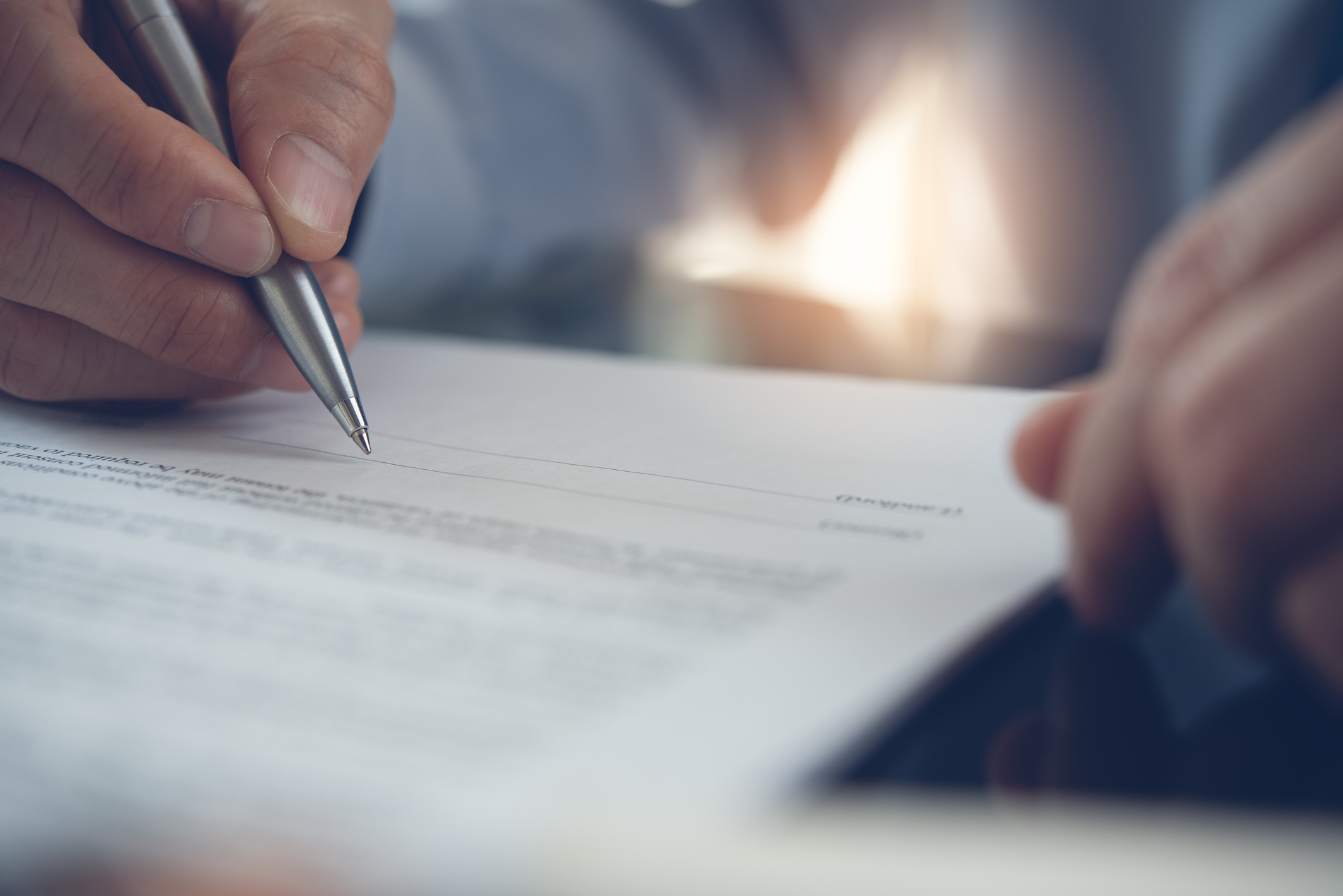 Close up image of someone signing a document